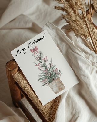 Christmas card with floral design on a wooden stool with white fabric background